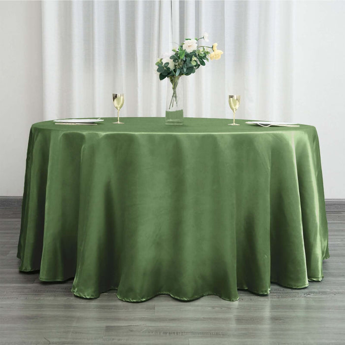 Green tablecloth draped over a round table with floral centerpiece and glasses.