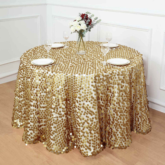 Gold sequin tablecloth on round table with plates and floral centerpiece.