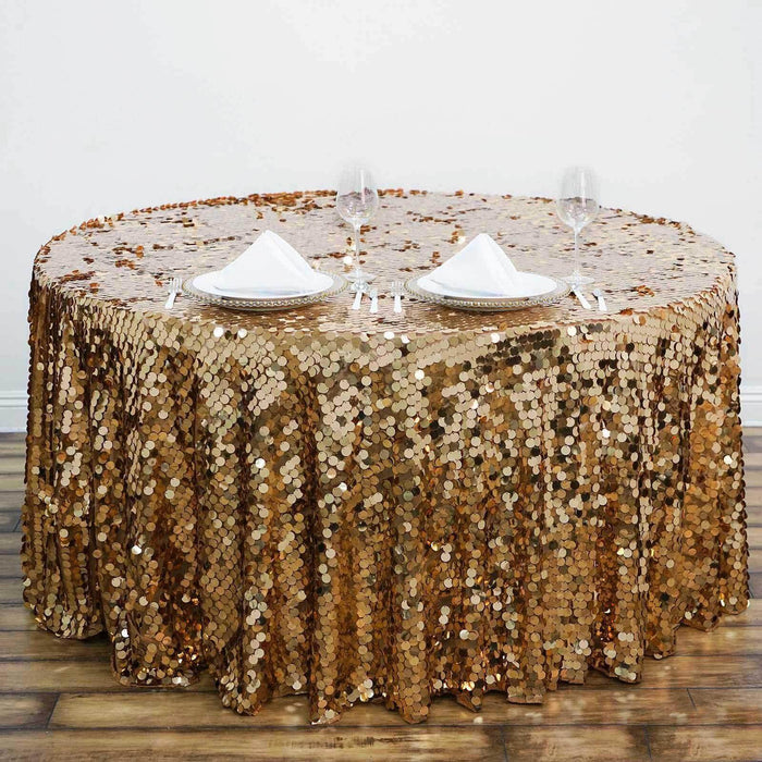 Gold sequin tablecloth on a round table set with plates and glasses.