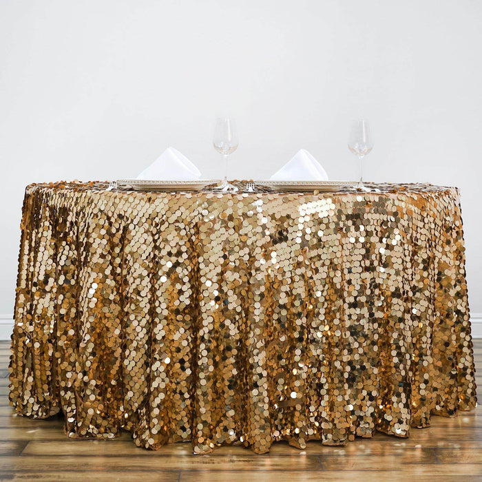 Gold sequin tablecloth draped over a table with glasses and napkins.