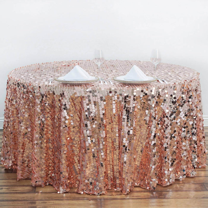 Rose gold sequin tablecloth draped over a round table with elegant dinnerware.