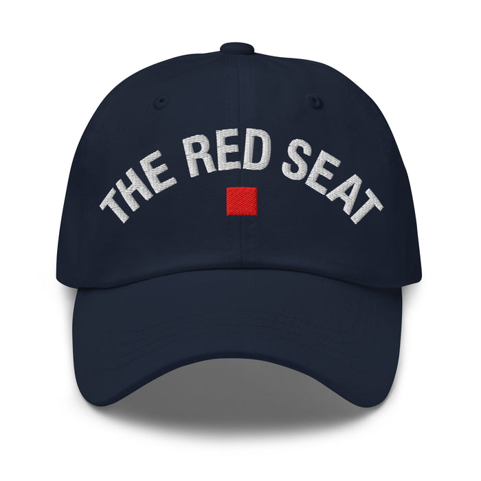 Front view of navy dad cap with “The Red Seat” embroidered in white and red icon