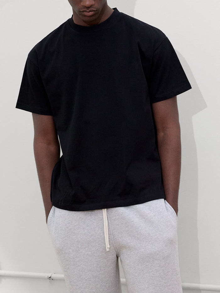 close up of male model wearing black tshirt and heather gray sweatpants by one dna