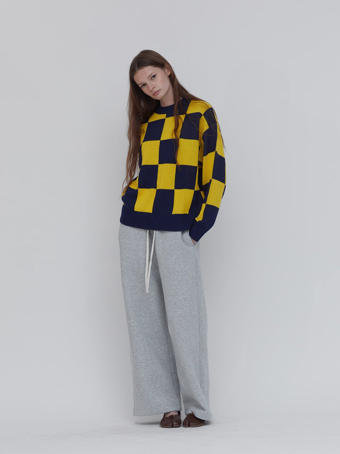 A women wears blue and yellow-checkerboard sweater by One Dna