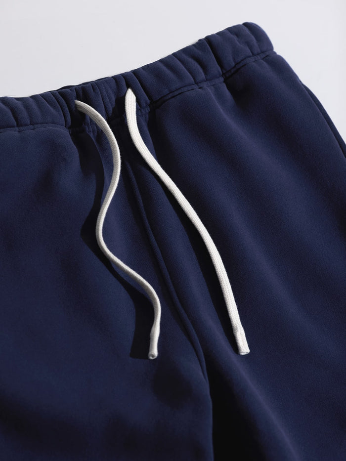 Detail of ONE DNA navy blue sweatpants with white drawstring on a gray background